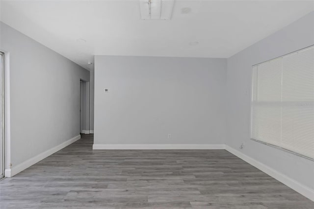 spare room featuring baseboards, visible vents, and wood finished floors