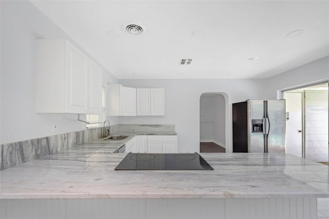 kitchen with stainless steel refrigerator with ice dispenser, kitchen peninsula, sink, black electric cooktop, and white cabinets