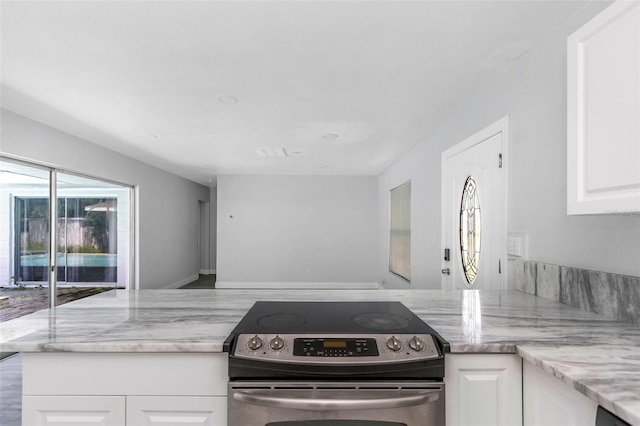 kitchen featuring white cabinetry, stainless steel electric range oven, and light stone countertops