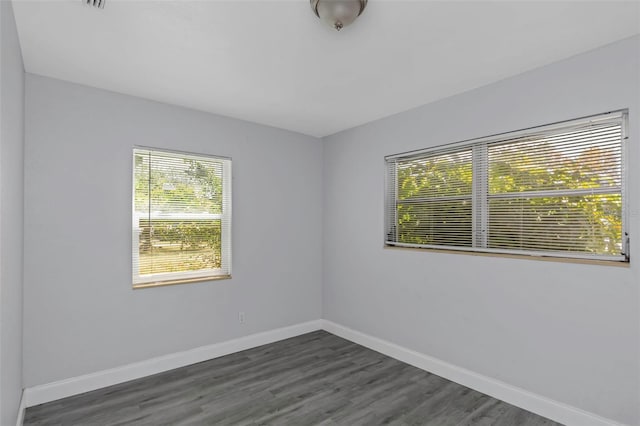 spare room with baseboards and dark wood finished floors