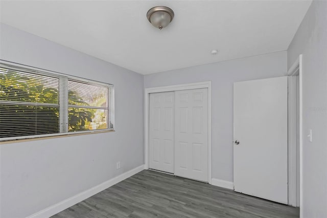 unfurnished bedroom with a closet, wood finished floors, and baseboards