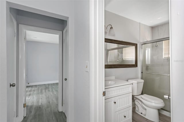 bathroom with a shower with door, vanity, toilet, and wood finished floors