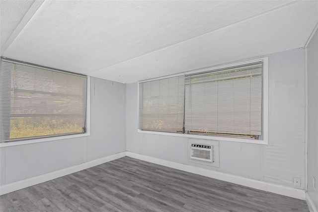 spare room with a textured ceiling, an AC wall unit, and hardwood / wood-style flooring