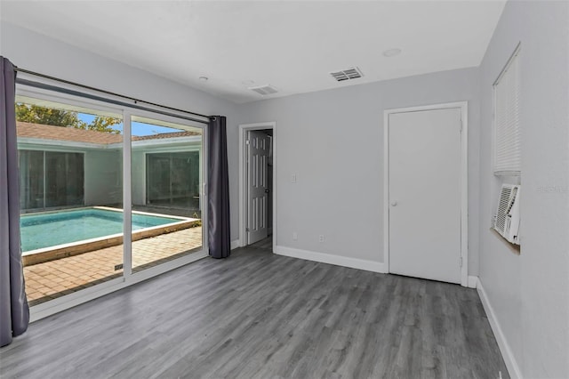 spare room featuring baseboards, visible vents, and wood finished floors