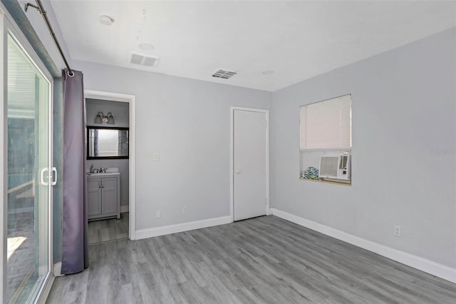 unfurnished bedroom featuring light wood finished floors, baseboards, visible vents, and a sink