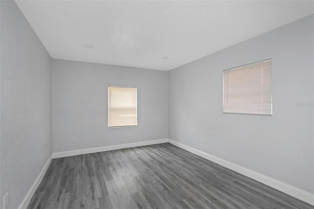 unfurnished room with dark wood finished floors and baseboards