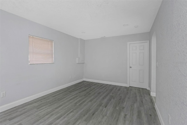 unfurnished room with a textured ceiling and wood-type flooring