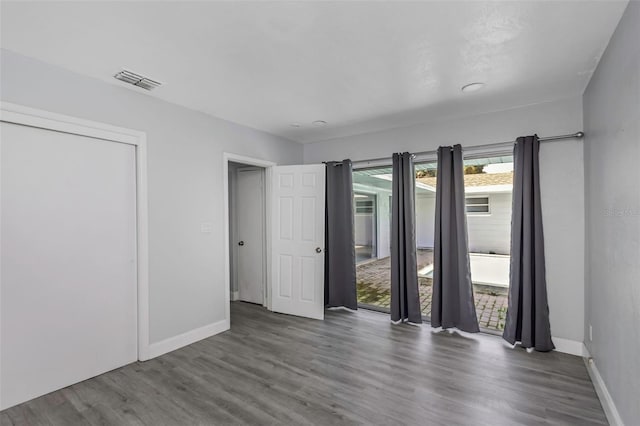 unfurnished bedroom with baseboards, visible vents, and wood finished floors