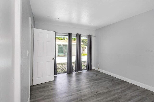 unfurnished room with dark wood-type flooring and baseboards