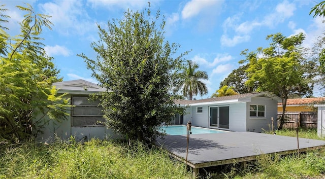 rear view of property featuring fence, a deck, and a fenced in pool