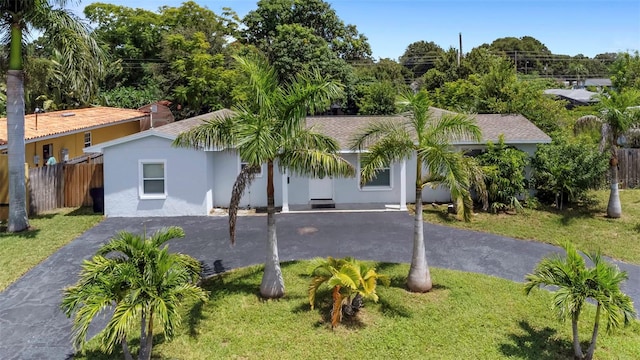 back of property featuring a yard, aphalt driveway, fence, and stucco siding