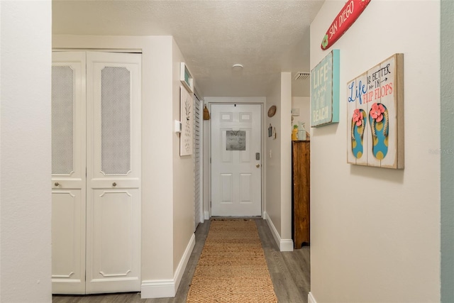 hallway with a textured ceiling and hardwood / wood-style flooring