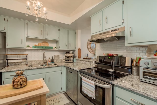 kitchen with stainless steel appliances, an inviting chandelier, sink, decorative backsplash, and a tray ceiling