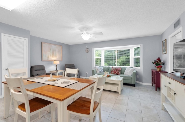 tiled dining area featuring a textured ceiling and ceiling fan