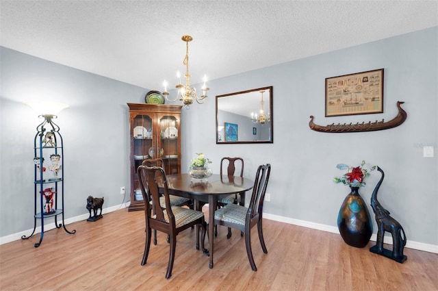 dining room featuring a textured ceiling, an inviting chandelier, and light wood-type flooring