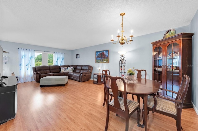 dining room featuring light wood-type flooring, an inviting chandelier, and a textured ceiling