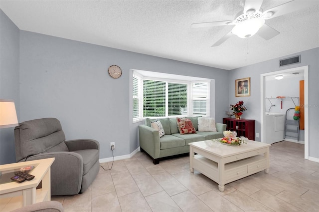 living room featuring a textured ceiling, ceiling fan, and washer / clothes dryer