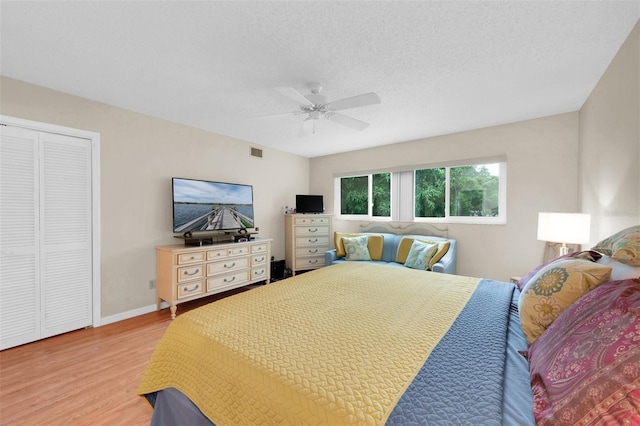 bedroom with a closet, ceiling fan, a textured ceiling, and light hardwood / wood-style flooring