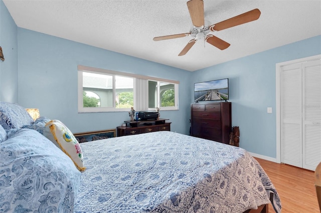 bedroom with a textured ceiling, ceiling fan, a closet, and light wood-type flooring