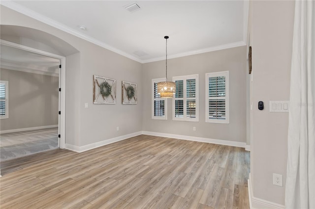 spare room with light wood-type flooring, ornamental molding, and a chandelier