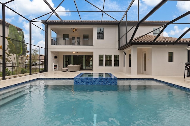 rear view of house with ceiling fan, a pool with hot tub, a lanai, a balcony, and a patio area