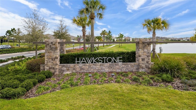 community / neighborhood sign featuring a yard and a water view