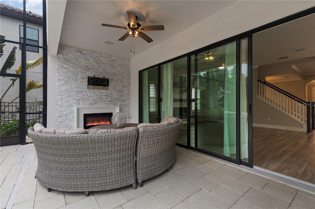 view of patio with an outdoor living space with a fireplace and ceiling fan