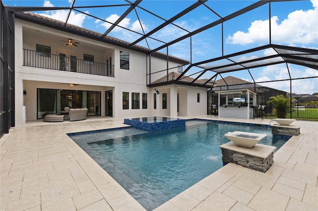 view of swimming pool featuring glass enclosure, an in ground hot tub, ceiling fan, and a patio