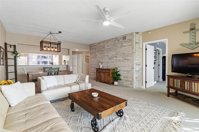 carpeted living room with a textured ceiling and ceiling fan with notable chandelier