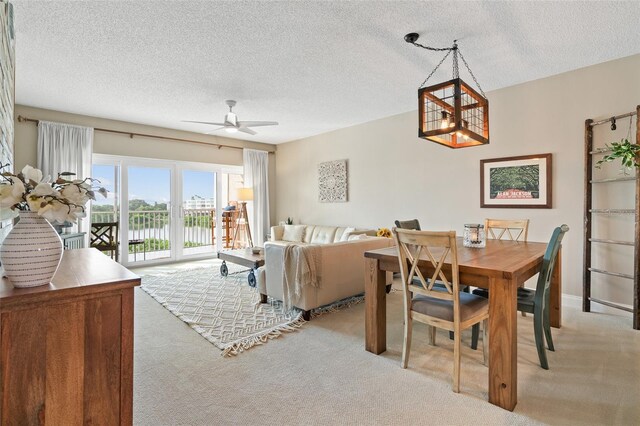 dining area with ceiling fan, a textured ceiling, and light colored carpet