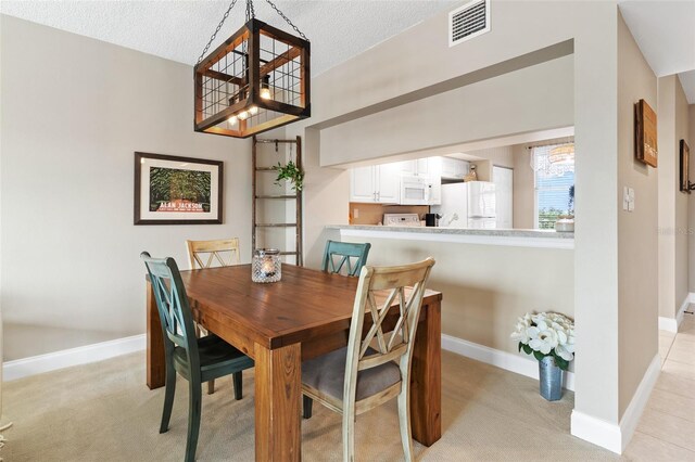 carpeted dining area featuring a textured ceiling