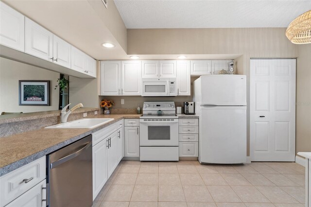 kitchen featuring white cabinetry, sink, light tile patterned floors, and white appliances