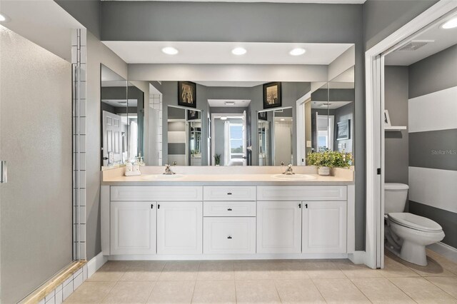 bathroom with vanity, a shower with shower door, toilet, and tile patterned flooring