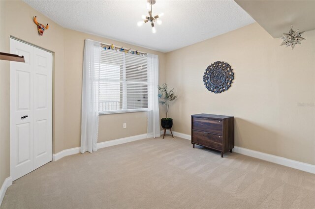 interior space featuring a closet, light carpet, a notable chandelier, and a textured ceiling