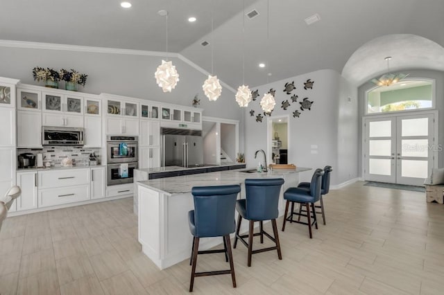 kitchen featuring a breakfast bar area, decorative light fixtures, appliances with stainless steel finishes, french doors, and a large island