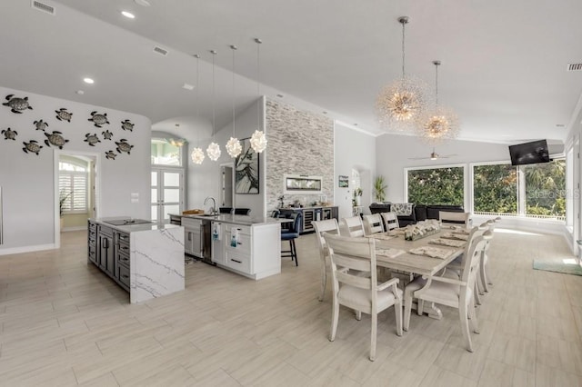 dining room with a healthy amount of sunlight, sink, ceiling fan with notable chandelier, and high vaulted ceiling