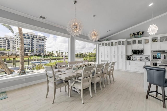 dining space featuring lofted ceiling, ornamental molding, and a chandelier