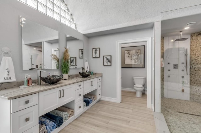 bathroom with a textured ceiling, vanity, hardwood / wood-style floors, walk in shower, and toilet