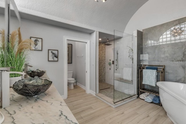 full bathroom featuring a textured ceiling, separate shower and tub, hardwood / wood-style floors, toilet, and a chandelier