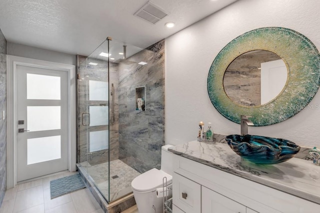 bathroom with tile patterned flooring, an enclosed shower, toilet, vanity, and a textured ceiling