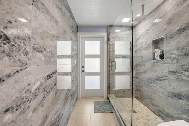 bathroom featuring a shower with door, plenty of natural light, toilet, and tile patterned floors