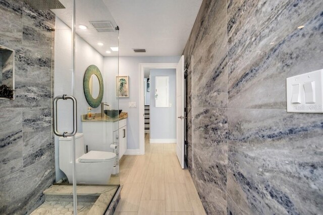 bathroom featuring toilet, a shower with door, and vanity