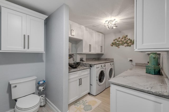 washroom featuring a textured ceiling, washing machine and dryer, sink, and light wood-type flooring