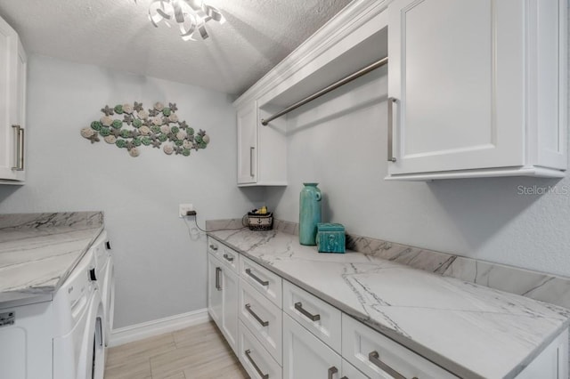 kitchen featuring light wood-type flooring, white cabinetry, and a textured ceiling