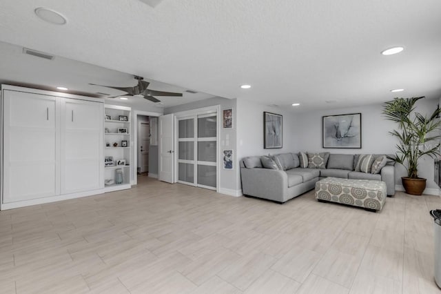 living room featuring built in shelves and ceiling fan