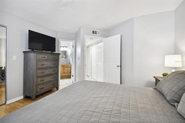 bedroom featuring light hardwood / wood-style flooring, a closet, and ensuite bathroom