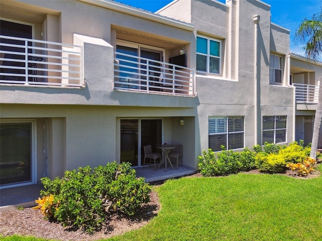 back of property featuring a yard, a patio area, and a balcony