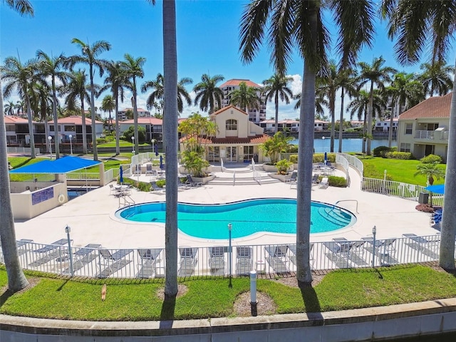 view of pool with a water view, a lawn, and a patio