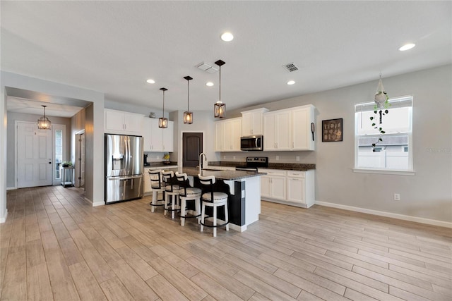 kitchen featuring appliances with stainless steel finishes, plenty of natural light, an island with sink, and a kitchen breakfast bar