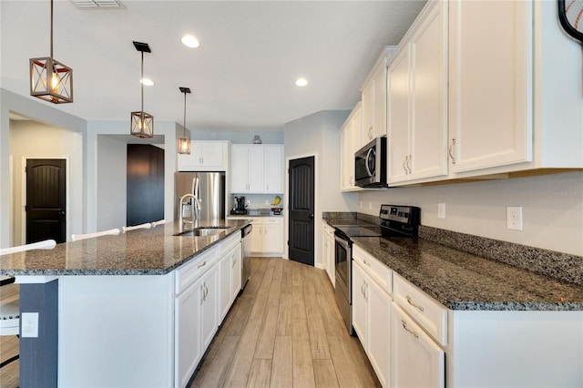 kitchen featuring light hardwood / wood-style flooring, appliances with stainless steel finishes, white cabinetry, sink, and a center island with sink